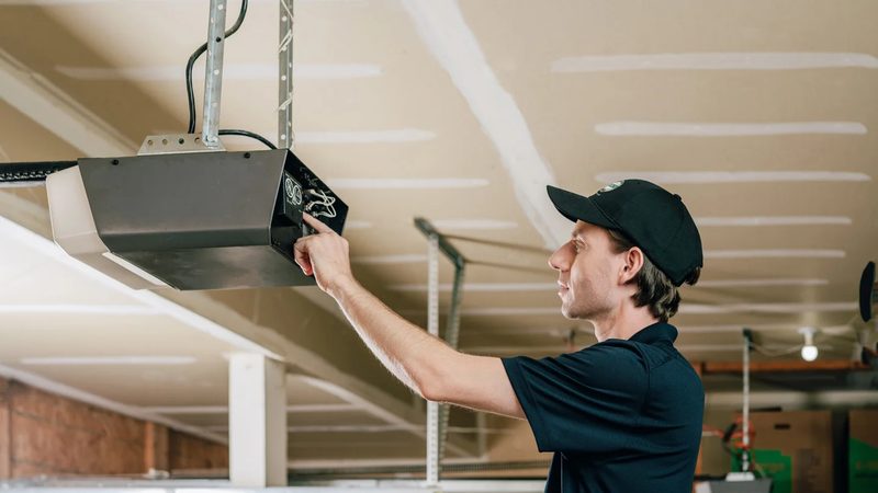 Technician adjusting garage door opener motor — Los Angeles