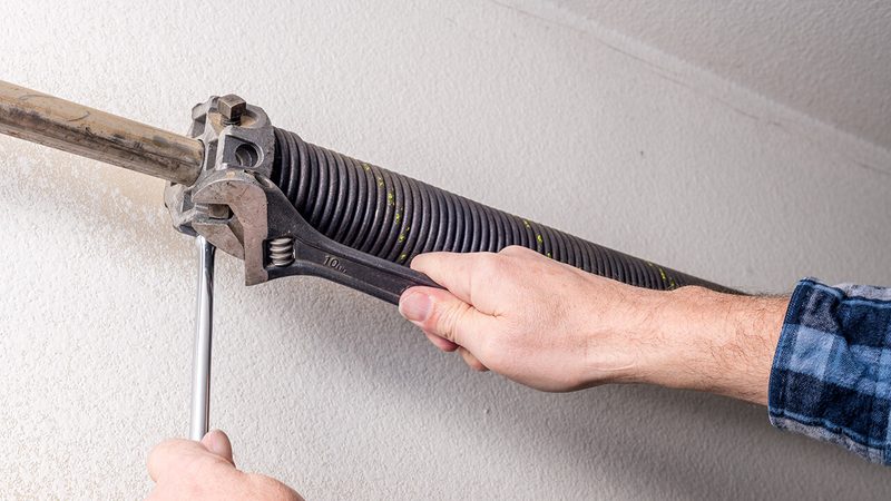 Technician winding torsion spring — garage door spring repair Los Angeles