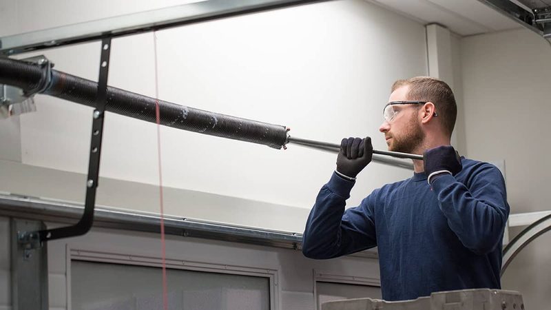 Technician on ladder replacing torsion spring — Los Angeles garage door repair