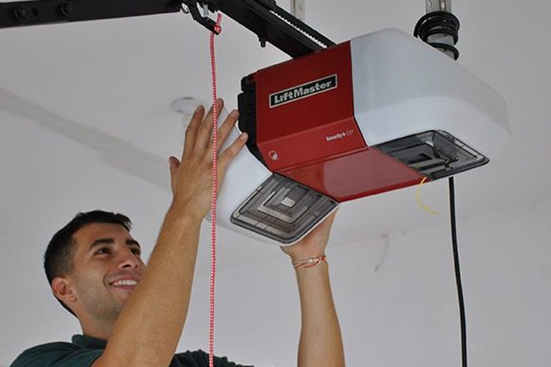 Technician on a ladder repairing a LiftMaster garage door opener