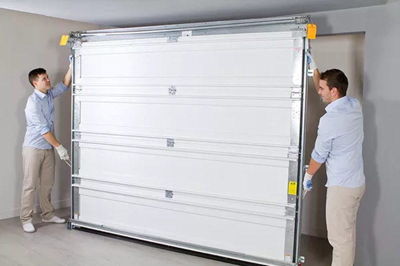 Two M&M garage door technicians working transparently on a new door install